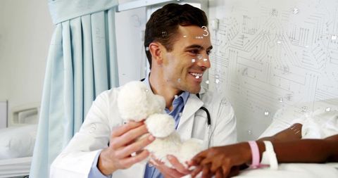 Compassionate pediatrician giving teddy bear to young patient