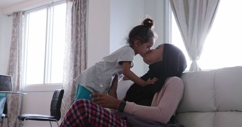 Loving mother and daughter bonding together on sofa
