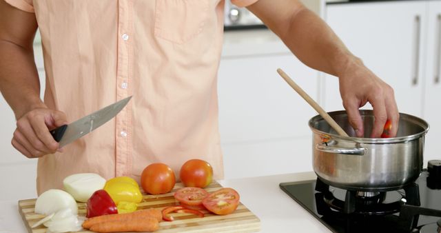 Man chopping fresh vegetables on kitchen counter for homemade meal. Suitable for content promoting healthy eating, home cooking, culinary tutorials, and kitchen appliance advertisements.