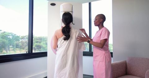 Patient receiving mammogram screening with compassionate female technician in radiology