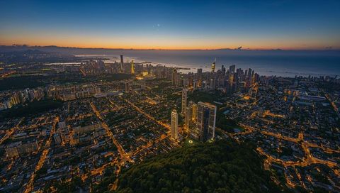 Twilight Coastal Skyline with Illuminated High-Rise Trio and Harbor Lights from Aerial View