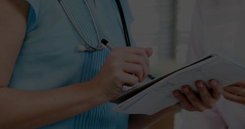 Healthcare Professional Writing on Clipboard in Exam Room