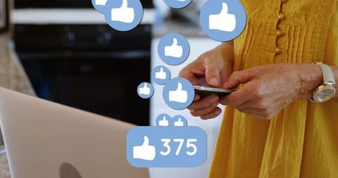 Senior tapping smartphone at kitchen counter receiving social likes and follower growth