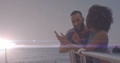 Romantic Couple Enjoying Sunset by Oceanside with Smartphone