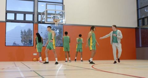 Diverse Basketball Team Training under Coach's Guidance in Indoor Gym