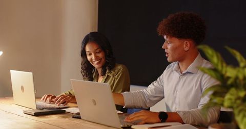 Diverse Colleagues Collaborating on Laptops in Modern Office