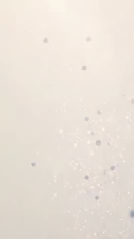 Vertical beige bokeh particles drifting and sparkling with hexagon confetti