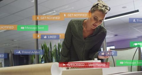 Designer leaning over architectural scale model with social media notification overlays