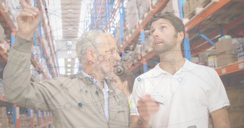 Warehouse managers inspecting inventory with digital network overlay, clipboard and handheld device