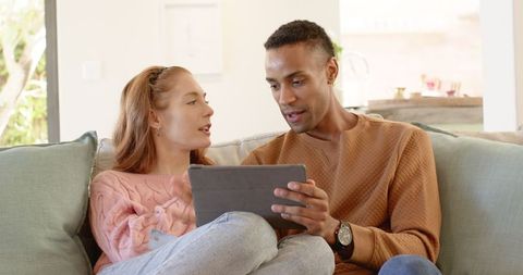 Diverse couple engaging with tablet in cozy living room
