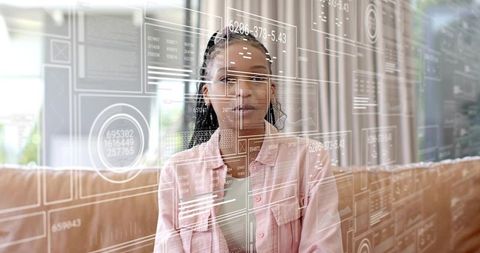 Young woman viewing augmented reality data panels over living room sofa