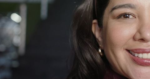 Warm closeup portrait smiling woman with gold hoop earring and soft bokeh background