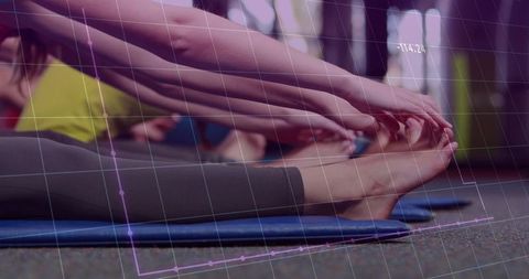 Women executing seated forward bend yoga stretch at gym