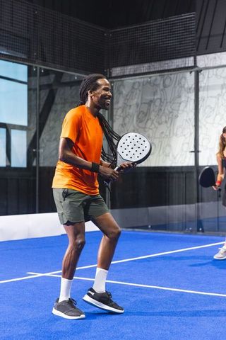 Excited Player Engaging in Doubles Padel Match on Indoor Blue Court