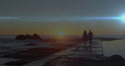 A couple walks on a concrete pier toward the glowing twilight sun, adding a touch of romance and adventure by the sea. Alongside rocks and a tidal pool, the scene evokes tranquility and serenity. Ideal for themes of romance, coastal travel, or peaceful seascape visuals, perfect for use in travel brochures, romantic getaways, or inspirational content highlighting serene coastal settings.