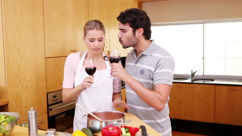 Young Couple Enjoys Wine While Cooking at Home