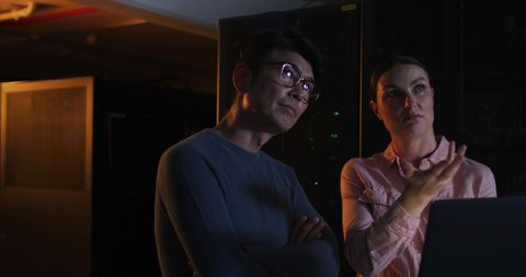 Professionals Analyzing Data in Dark Server Room