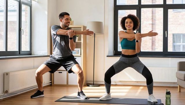 Couple performing home workout stretching and squats in sunlit living room