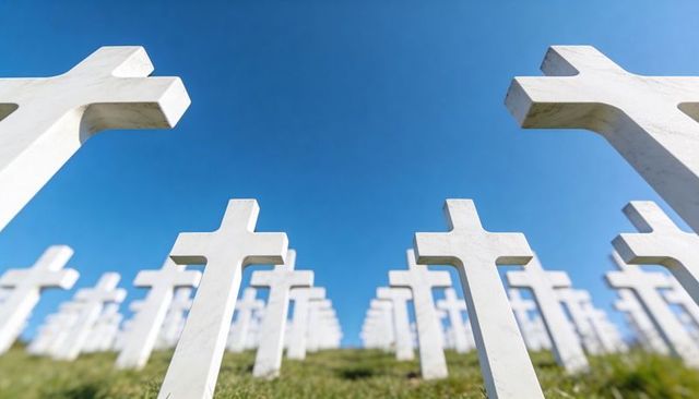 Sunlit rows of white stone crosses on memorial cemetery slope, strong perspective