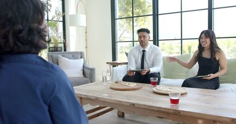 Sharing pizza and laughing together in bright modern living room