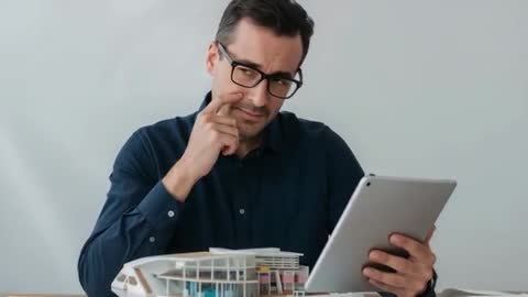 Architect Reviewing Scale Building Model While Comparing Plans on Tablet