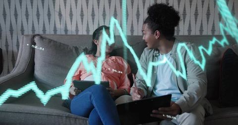Collaborating on financial analytics while holographic teal graph overlaying tablet screens