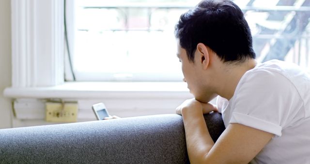 Young Man Looking at Smartphone While Relaxing on Sofa - Download Free Stock Images Pikwizard.com