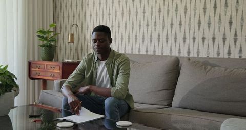 Man Writing on Clipboard in Contemporary Living Room