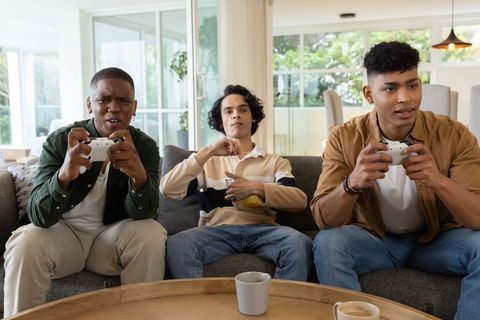 Diverse male friends competing in intense console game night holding white controllers in cozy moder