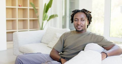 African american man relaxing on modern sofa in sunlit minimalist living room