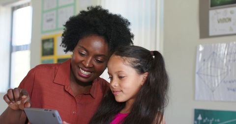 African American Teacher Supporting Student Using Tablet in Classroom Tutoring Moment