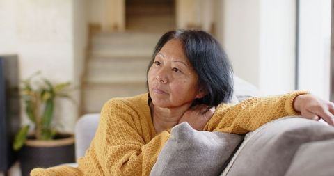 Senior Woman in Yellow Sweater Relaxing on Sofa at Home