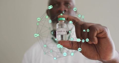 Senior healthcare worker holding covid-19 vaccine vial with holographic digital network