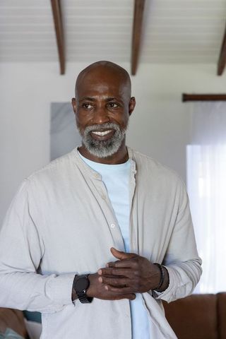 Senior african man smiling in cozy living room with vaulted beams and casual style