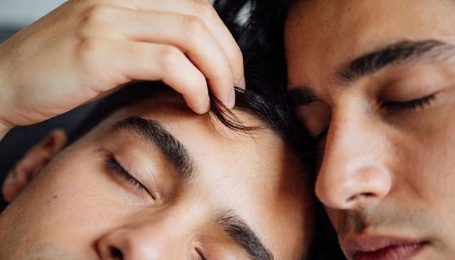 Intimate closeup of two male partners resting together showing tenderness and affection