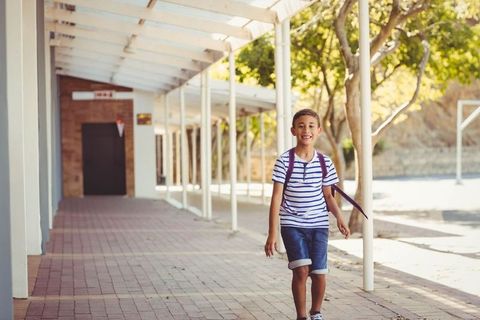 Schoolboy Walking Outdoors Carrying Backpack Under Covered Walkway