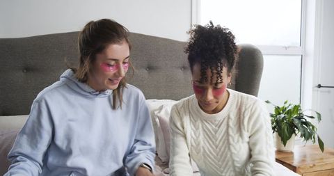 Friends relaxing with pink under-eye patches during cozy at-home skincare routine