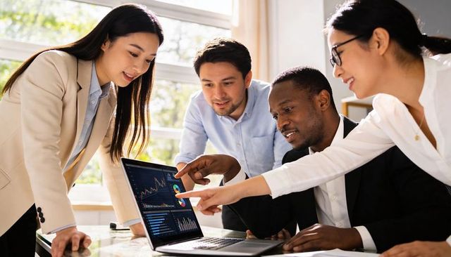 Diverse Team Analyzing Interactive Dashboards on Laptop During Collaborative Meeting
