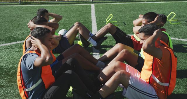 Diverse male football players training and doing sit-ups on outdoor pitch - Download Free Stock Photos Pikwizard.com