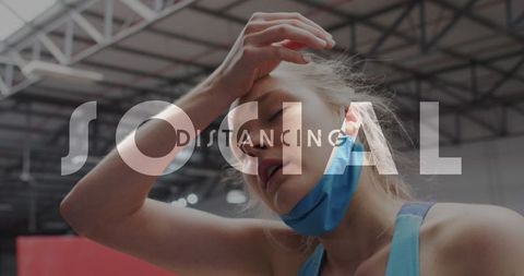 Exhausted woman with mask in gym emphasizing social distancing