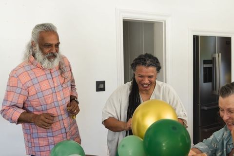 Multigenerational family arranging green and gold balloons for joyful home celebration