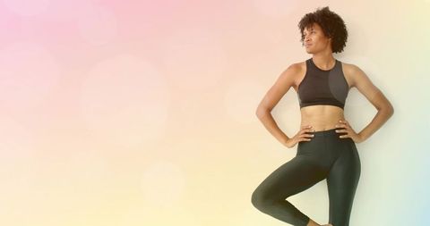 Confident athletic woman posing in activewear on pastel gradient backdrop with copy space