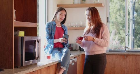 Mother and Daughter Chat at Kitchen Counter in Warm Sunlight