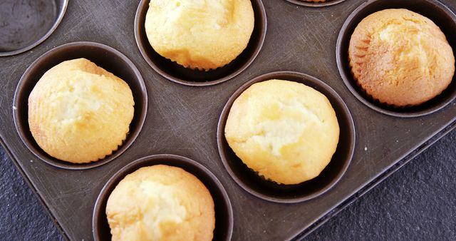 Freshly baked muffins cooling in a muffin tray, perfect for bakery promotions, recipes, cooking blogs, or food-related advertisements.