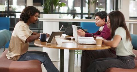 African American students collaborating and studying at round table in modern coworking space