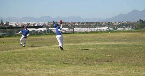 Baseball Players Catching Ball on Sunny Field