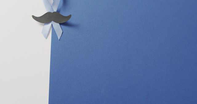 Blue cardstock with black mustache ribbon in top left corner, promoting Movember and men's health. Useful for flyers, posters, and online content related to men’s health awareness and promotional campaigns for prostate cancer screening and support. Ideal for providing information with an eye-catching design.