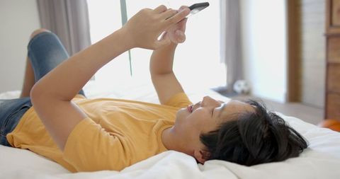 Asian college student relaxing with a smartphone, casual lifestyle
