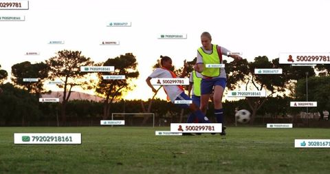 Youth soccer players sliding and controlling ball at sunset with floating digital id tags