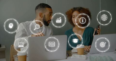 Business colleagues collaborating over laptops with augmented reality icons and smartphone